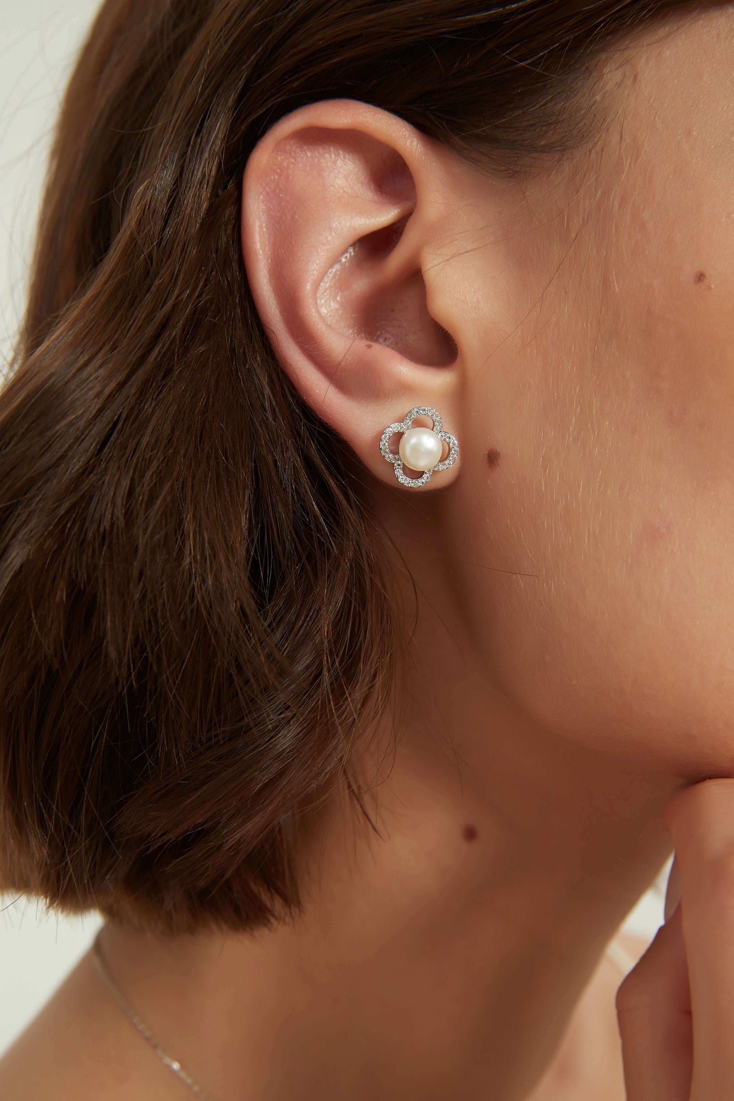 Eleanor earrings showcased on a model, featuring white cubic zirconia and freshwater pearls.